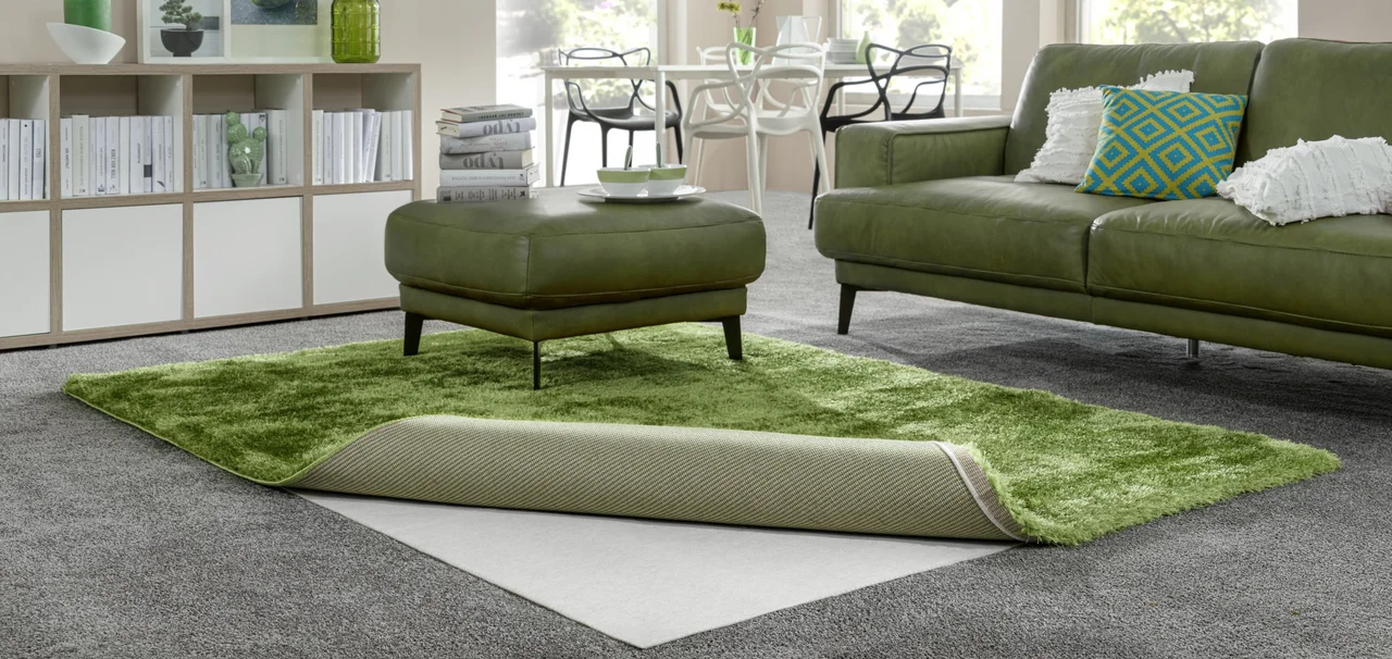 Wohnzimmer mit einem umgeschlagenen Teppich unter dem eine Teppichunterlage zu sehen ist. - Wohnzimmer mit einem umgeschlagenen Teppich unter dem eine Teppichunterlage zu sehen ist.